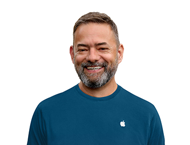 Showing an Apple Support Specialist smiling, wearing a blue shirt with an Apple logo on one side